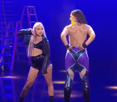 A Couple Of Women Are Standing Next To Each Other On A Stage . GIF