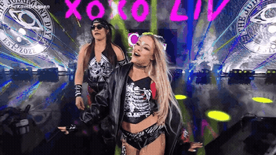A Couple Of Women Are Standing On A Stage In Front Of A Crowd . GIF