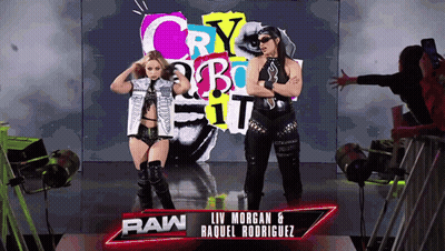 A Couple Of Women Standing In Front Of A Sign That Says Raw GIF