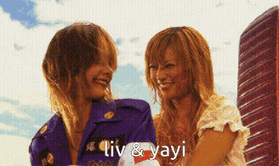 A Couple Of Women Standing Next To Each Other With The Words Liv & Yayi Written On The Bottom GIF