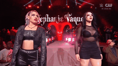 A Couple Of Women Standing On A Stage With The Name Stephanie Vaque Written On It GIF