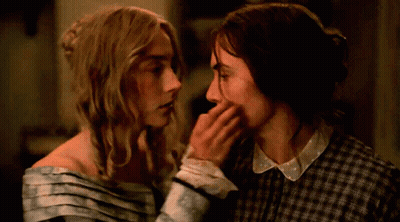 A Couple Of Women Touching Each Other 'S Faces In A Dark Room GIF