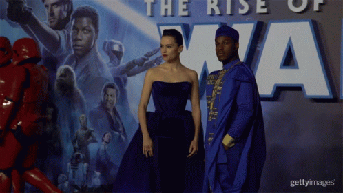 A Couple Standing In Front Of A Poster That Says The Rise Of Xna GIF