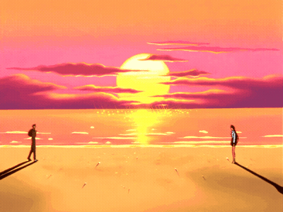 A Couple Standing On A Beach At Sunset GIF