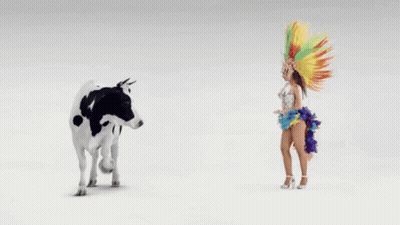 A Cow Is Standing Next To A Woman In A Colorful Outfit GIF