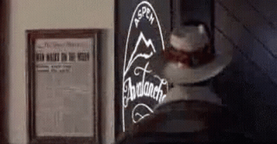 A Cowboy Hat Is Sitting On A Table Next To A Framed Newspaper And A Sign . GIF