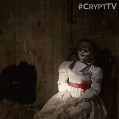 A Creepy Doll In A White Dress Is Sitting In A Chair GIF