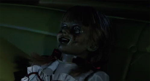 A Creepy Doll With Blood On Her Face And A Red Bow Around Her Neck GIF
