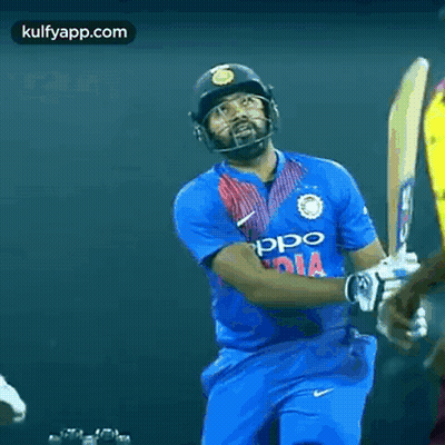 A Cricket Player In A Blue Jersey With The Word India On It Is Standing In Front Of Another Player . GIF