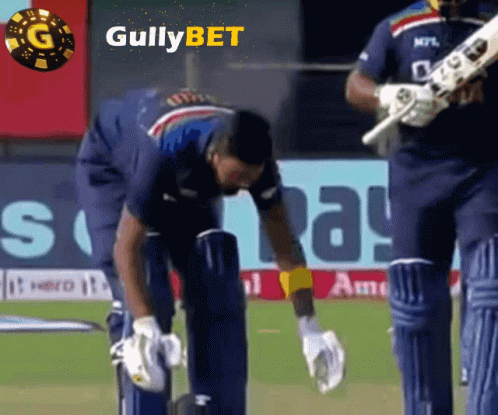 A Cricket Player Is Kneeling Down On The Field With A Gullybet Logo In The Background GIF