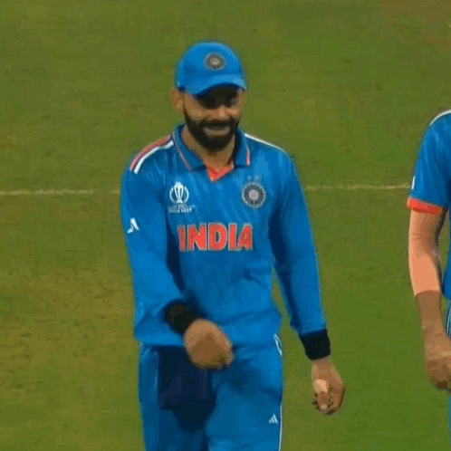 A Cricket Player Wearing A Blue Jersey With The Word India On It Is Standing On A Field . GIF