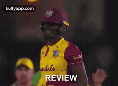 A Cricket Player Wearing A Helmet And Holding A Bat With The Word Review Written On It . GIF