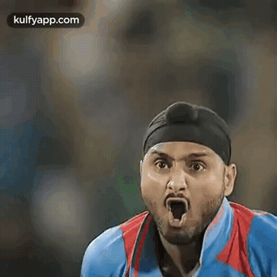 A Cricket Player Wearing A Turban And A Blue Shirt Is Standing On A Field . GIF