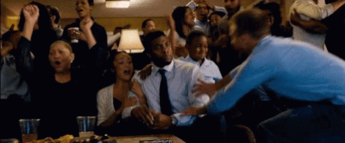 A Crowd Of People Are Gathered Around A Man In A Suit GIF