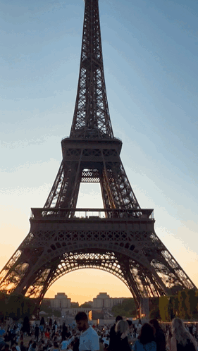 A Crowd Of People Are Gathered Around The Eiffel Tower In Paris GIF