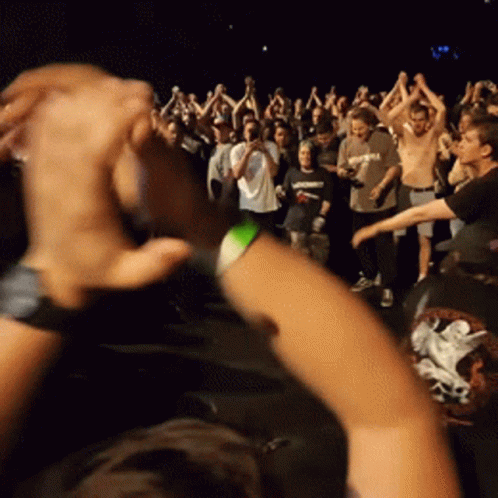 A Crowd Of People Are Gathered In A Dark Room GIF