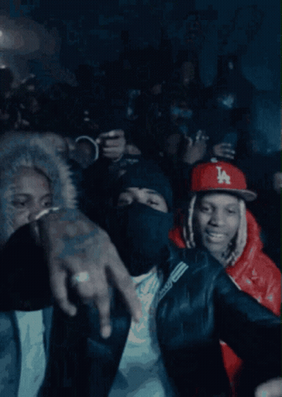 A Crowd Of People Are Gathered In A Dark Room And One Of Them Is Wearing A Ny Hat GIF