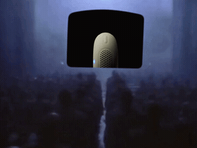 A Crowd Of People Are Gathered In A Dark Room With A Microphone Hanging From The Ceiling GIF
