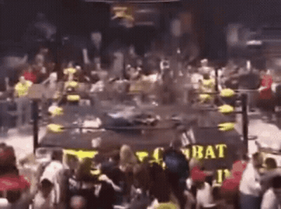 A Crowd Of People Are Gathered In Front Of A Sign That Says Combat . GIF