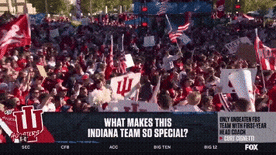 A Crowd Of People Are Gathered In Front Of A Sign That Says Indiana GIF