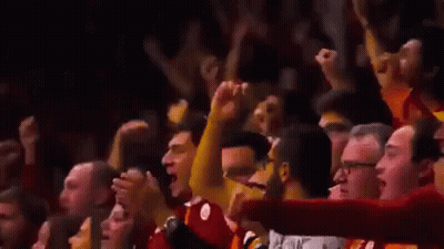A Crowd Of People Are Raising Their Arms In The Air At A Basketball Game . GIF