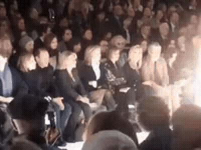 A Crowd Of People Are Sitting In A Stadium At A Fashion Show . GIF