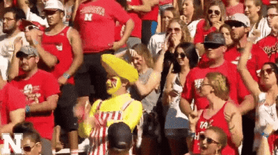 A Crowd Of People Are Sitting In A Stadium Wearing Red Shirts With The Letter N On Them GIF