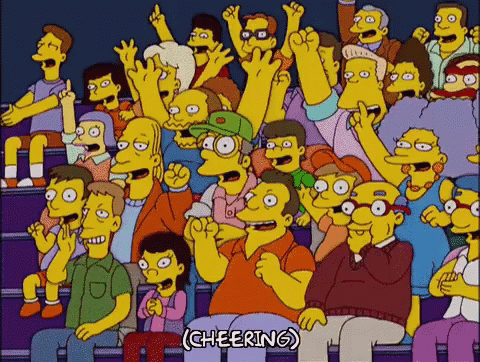 A Crowd Of People Are Sitting In A Stadium With Their Hands In The Air . GIF