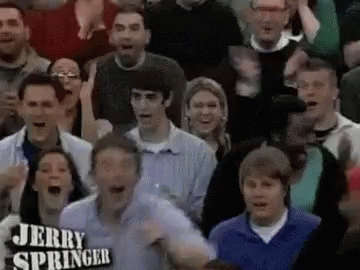 A Crowd Of People Are Watching A Game And One Of Them Is Wearing A Jerry Springer Shirt . GIF