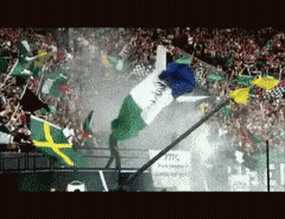 A Crowd Of People Are Watching A Race With Flags Flying In The Air GIF