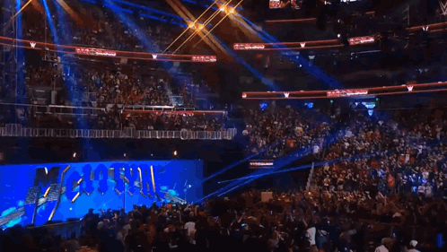 A Crowd Of People Are Watching A Wrestling Match In A Stadium With A Sign That Says ' Wwe ' On It GIF