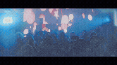 A Crowd Of People At A Concert With A Large Screen Behind Them That Says ' L ' GIF
