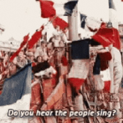 A Crowd Of People Holding Flags With The Words Do You Hear The People Sing Below Them GIF
