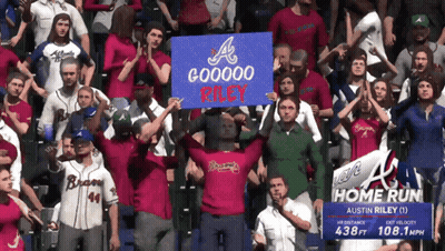 A Crowd Of People Holding Up A Sign That Says Gooooo Riley GIF