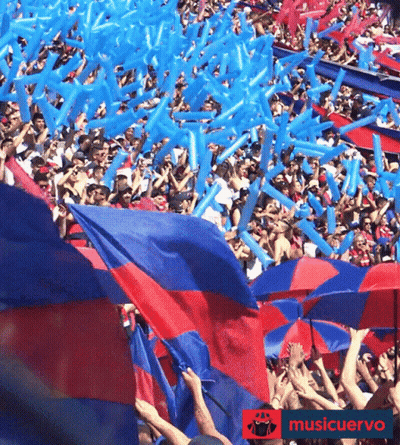 A Crowd Of People Holding Up Red And Blue Umbrellas And Balloons With The Words Musicuervo On The Bottom Right GIF