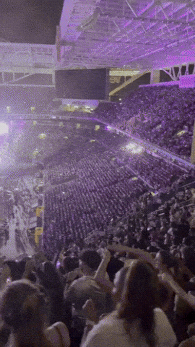 A Crowd Of People In A Stadium With Purple Lights GIF