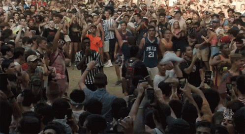 A Crowd Of People Including A Man Wearing A Jersey With The Number 21 On It GIF