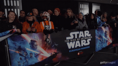 A Crowd Of People Standing In Front Of A Star Wars European Premiere Banner GIF
