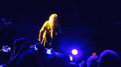 A Crowd Of People Watching A Concert With A Blue Light In The Background GIF