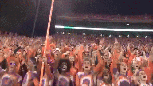 A Crowd Of People Wearing Orange And Purple Jerseys With The Number 3 On Them GIF