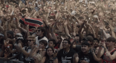 A Crowd Of People With One Wearing A Black Shirt That Says La Corona GIF