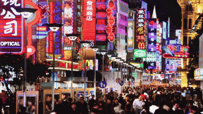 A Crowded City Street With A Sign That Says Optical GIF