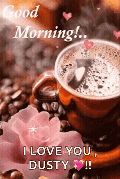 A Cup Of Coffee Is Sitting On Top Of Coffee Beans Next To A Pink Flower . GIF