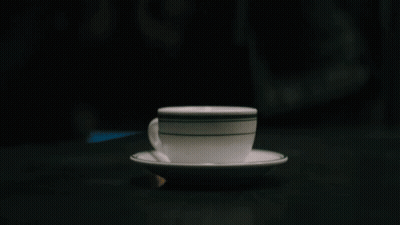 A Cup Of Coffee On A Saucer With A Black And White Stripe GIF