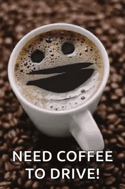 A Cup Of Coffee With A Smiley Face On It Is Sitting On A Pile Of Coffee Beans . GIF