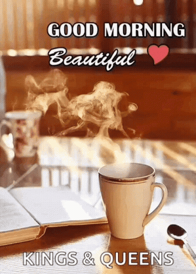 A Cup Of Coffee With Steam Coming Out Of It Is On A Table With A Book And A Spoon . GIF