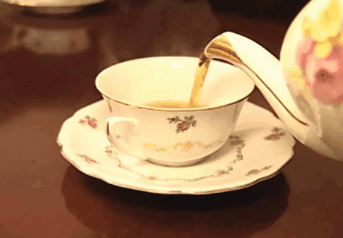 A Cup Of Tea Is Being Poured From A Teapot On A Saucer GIF