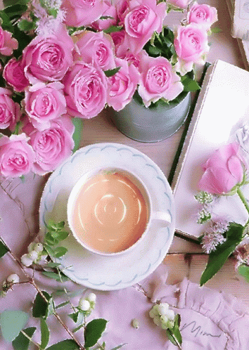 A Cup Of Tea Sits On A Saucer Next To A Book And Pink Roses GIF
