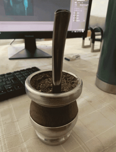 A Cup Of Yerba Mate Sits On A Table Next To A Computer Monitor GIF