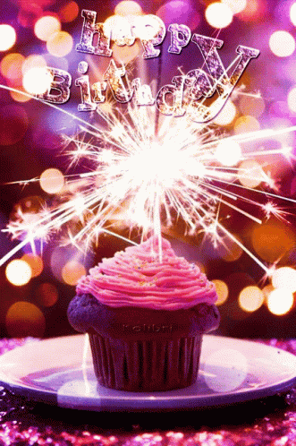 A Cupcake With Pink Frosting Is Surrounded By Sparklers With The Words Happy Birthday Written In The Background GIF